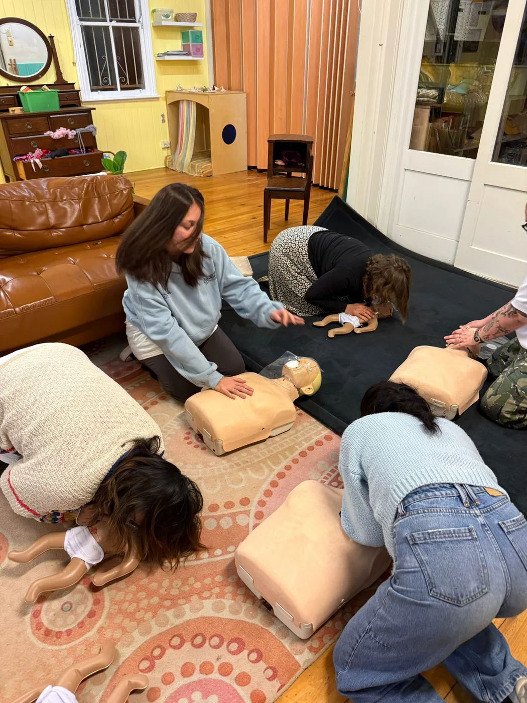 Early childhood educators practising CPR on manikins during group first aid training