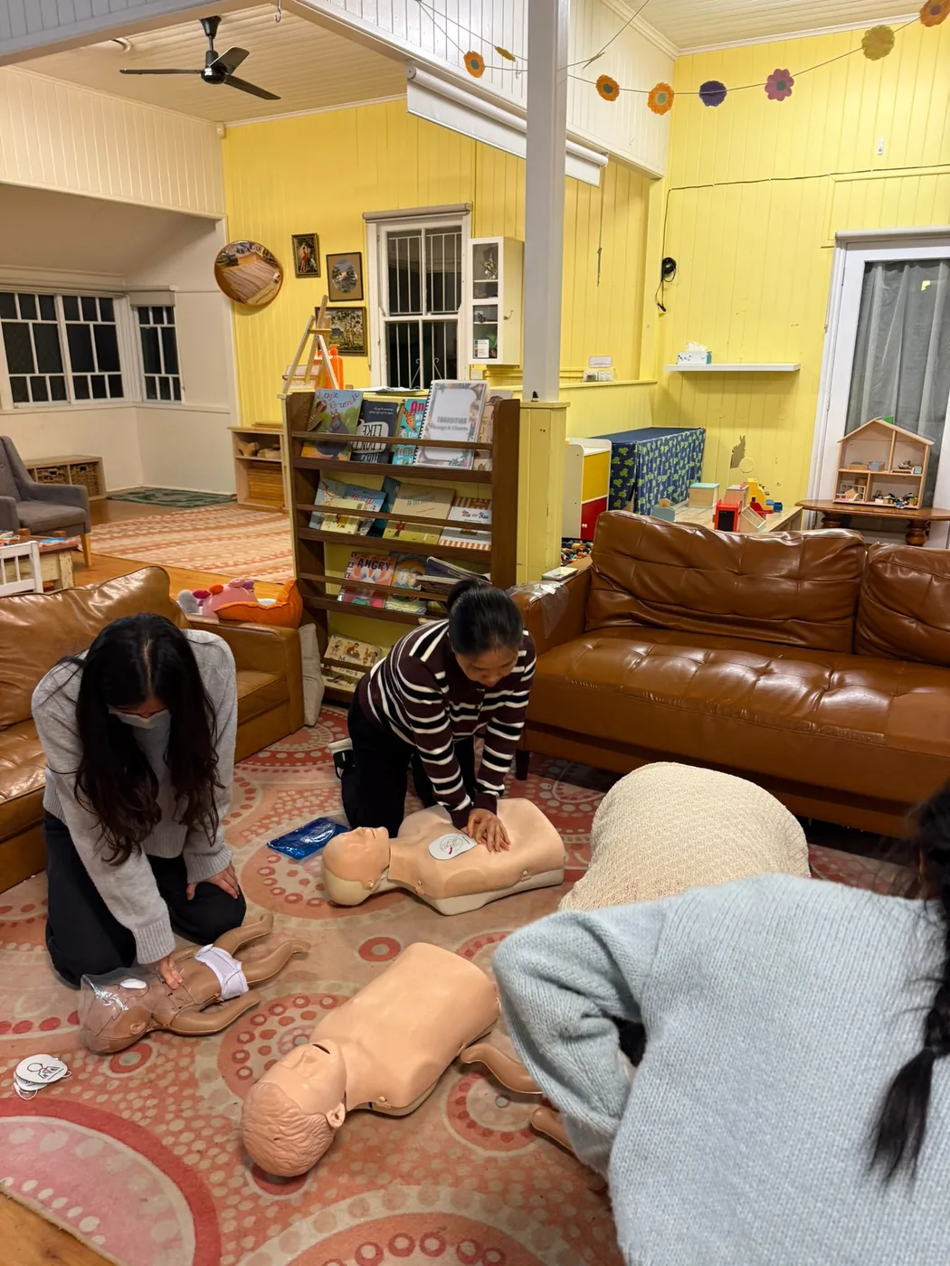 Childcare staff practising CPR on adult and infant manikins during onsite first aid training at a Gold Coast kindergarten