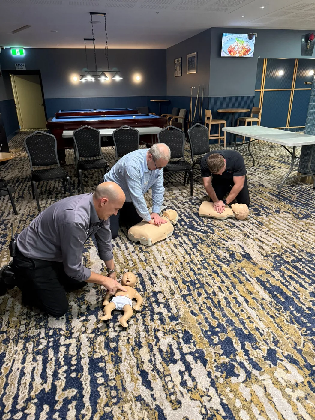 Hospitality staff practising CPR on adult and infant manikins during onsite first aid training at a Gold Coast venue