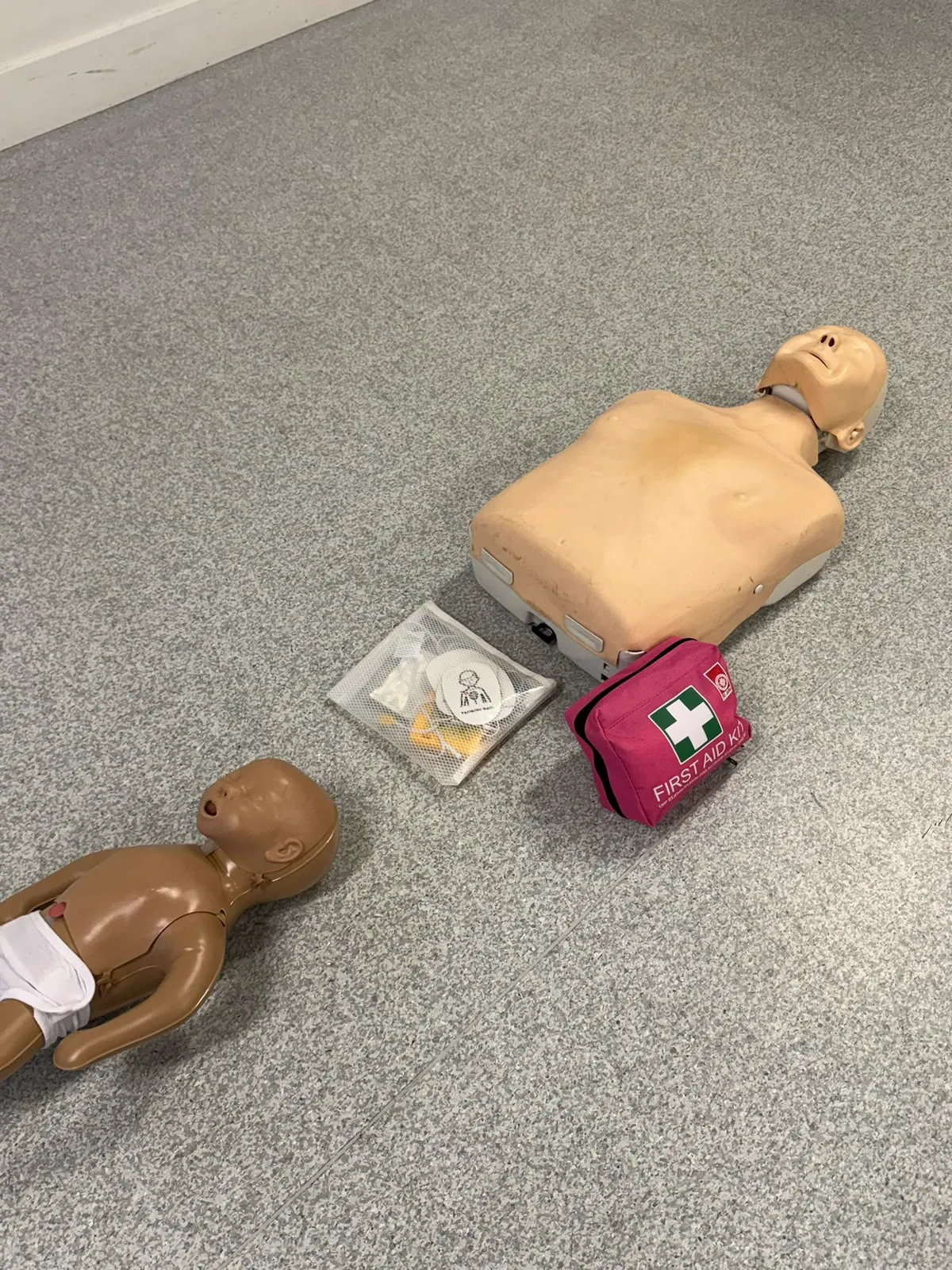 Adult and infant CPR manikins with first aid kit equipment ready for training